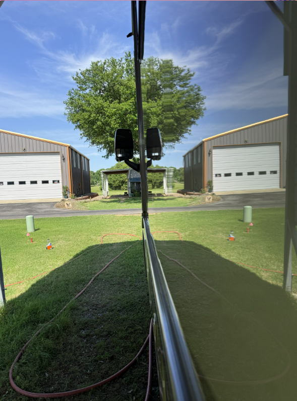 Freshly cleaned RV windshield with a clear view of the property